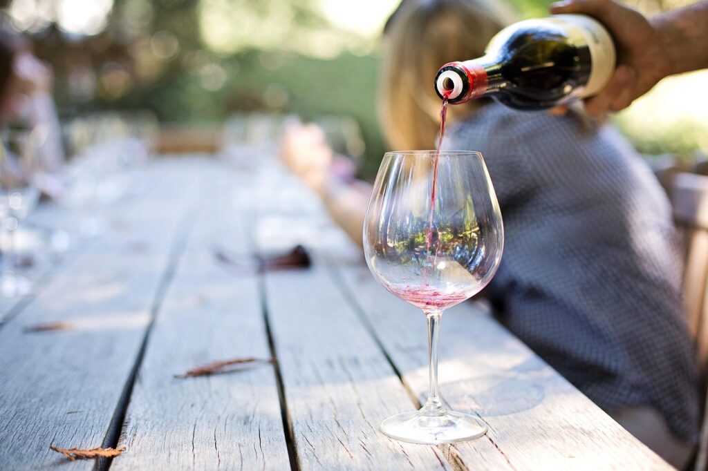 Rode wijn wordt ingeschonken in een glas aan een lange tafel buiten